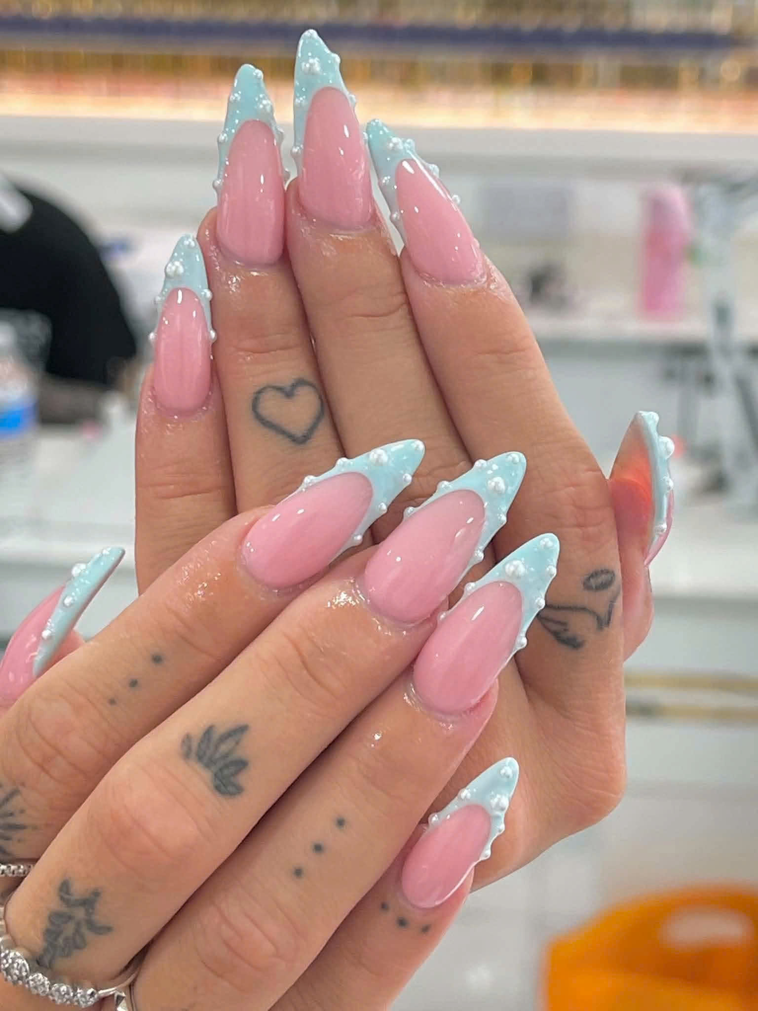 Pink and yellow nail extensions with black tips and raised floral detail