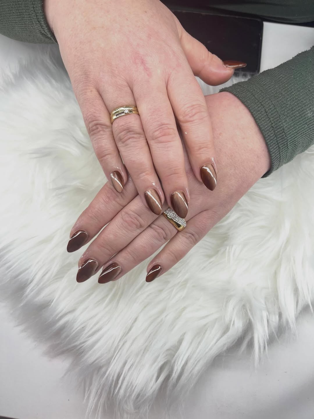 Verzorgde amandelvormige nagels in warme chocoladebruine tinten met gouden details